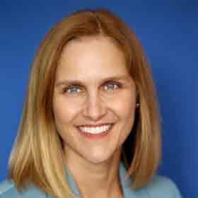 A woman is smiling for the camera in front of a blue background.