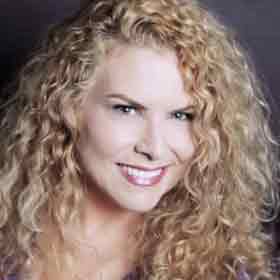 A woman with curly blonde hair is smiling for the camera.