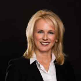 A woman in a suit and white shirt is smiling for the camera.