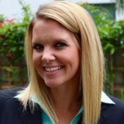 A woman in a suit and blue shirt is smiling for the camera.