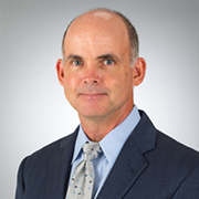 A bald man in a suit and tie is smiling for the camera.