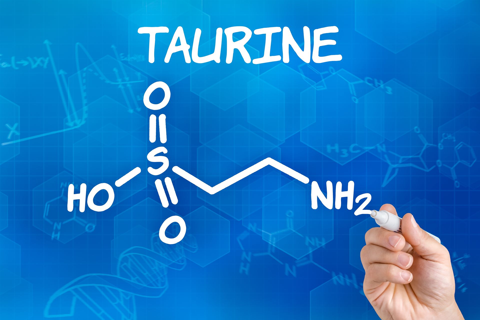 A person is writing the chemical structure of taurine on a blue board.
