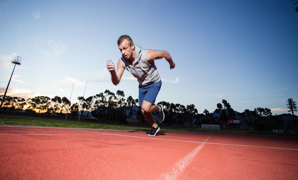 A man is running on a track at sunset.