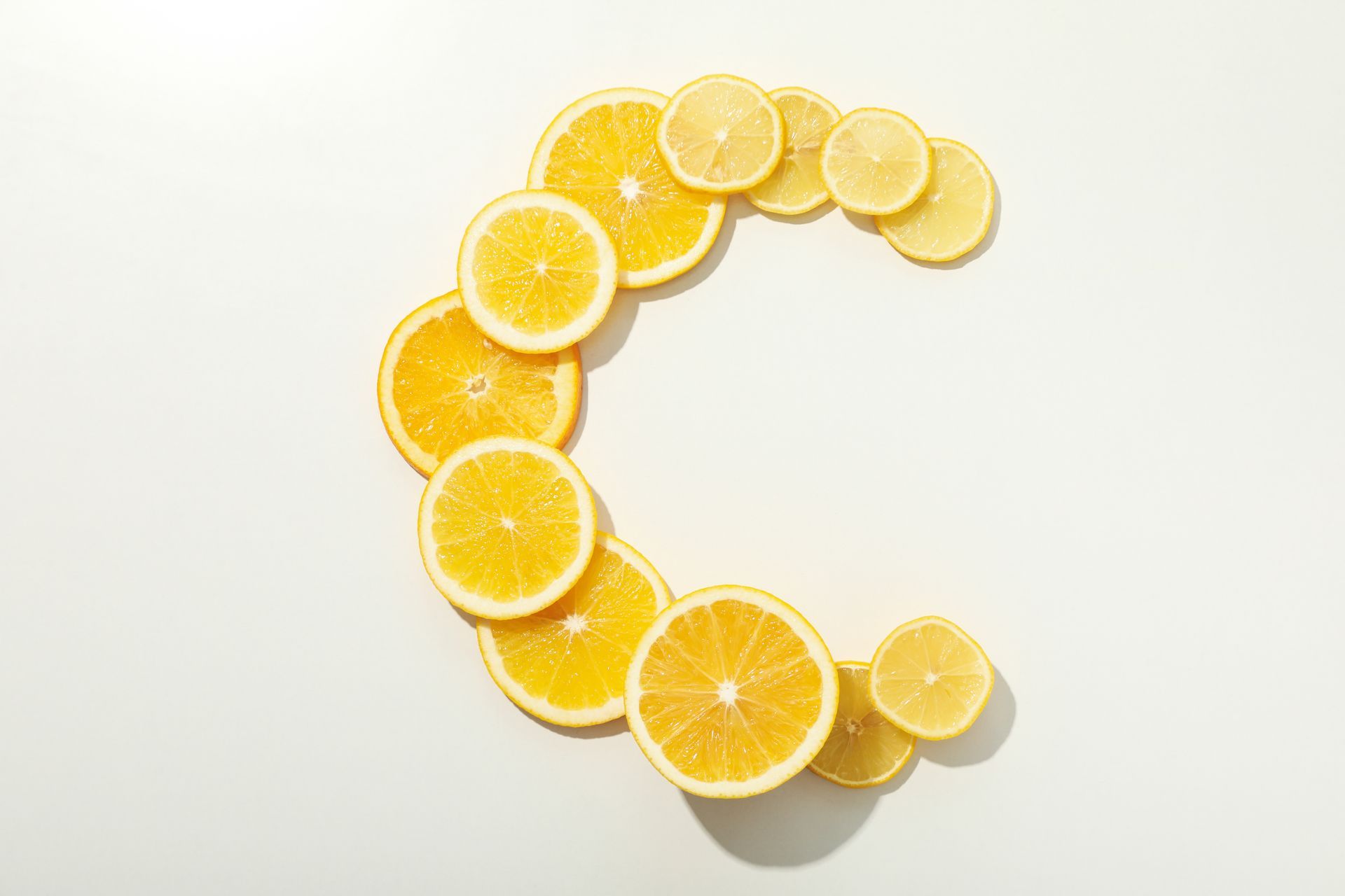 The letter c is made of sliced oranges and lemons on a white background.