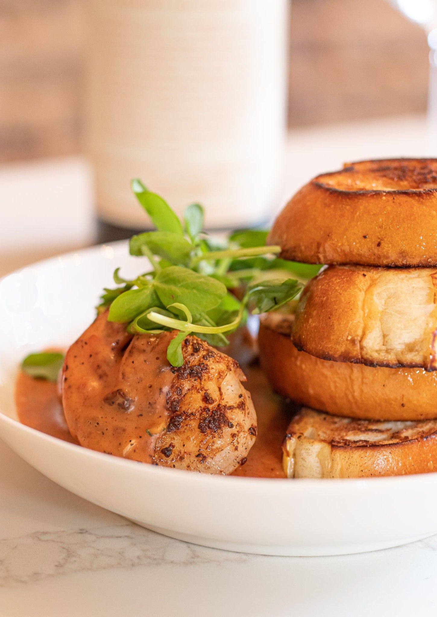 A close up of a plate of food with onion rings and meat on a table.