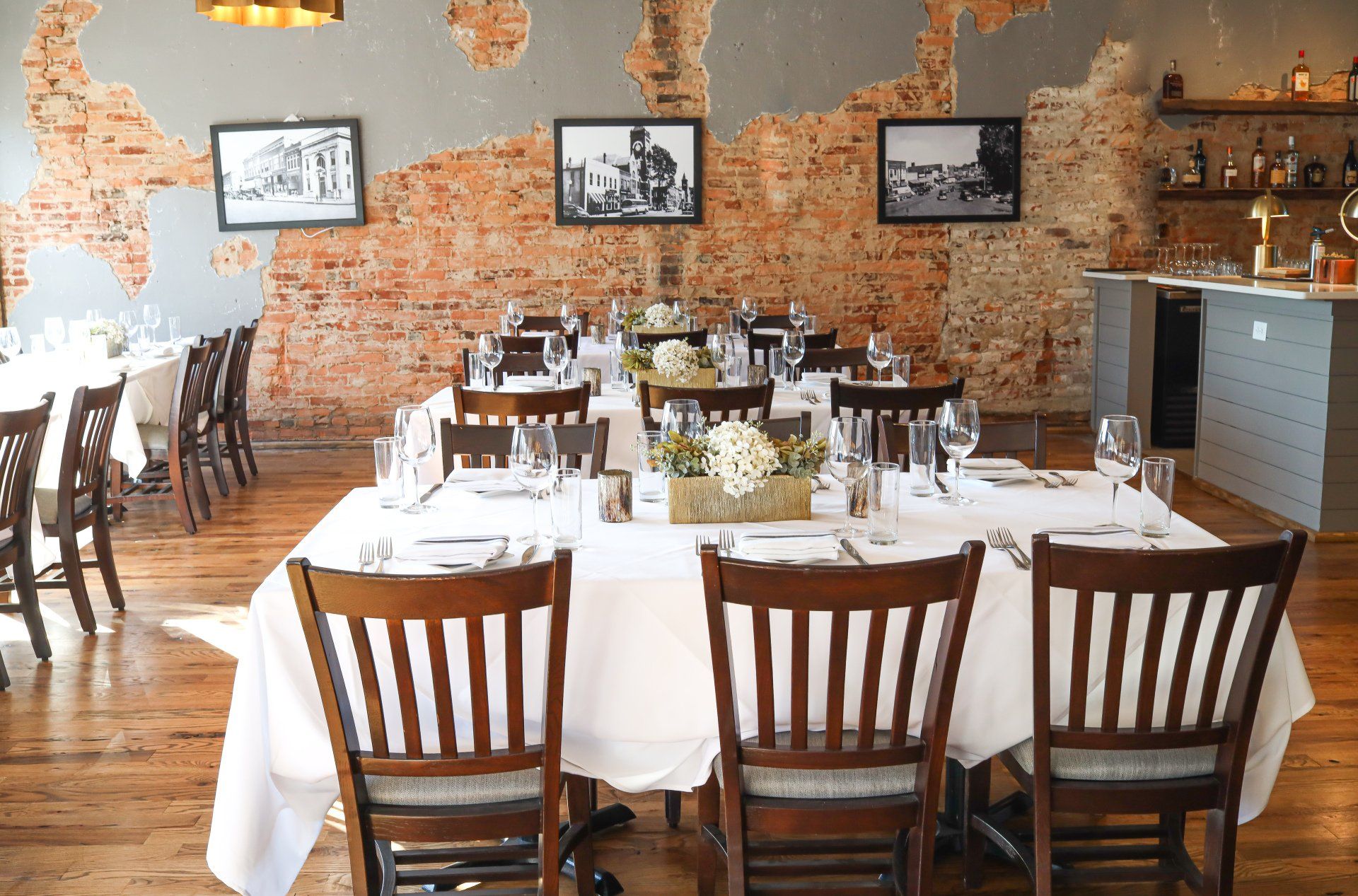 A dining room with tables and chairs and a brick wall.