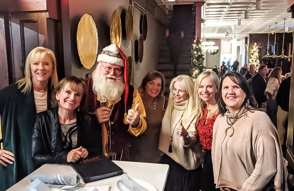 A group of women are posing for a picture with santa claus.