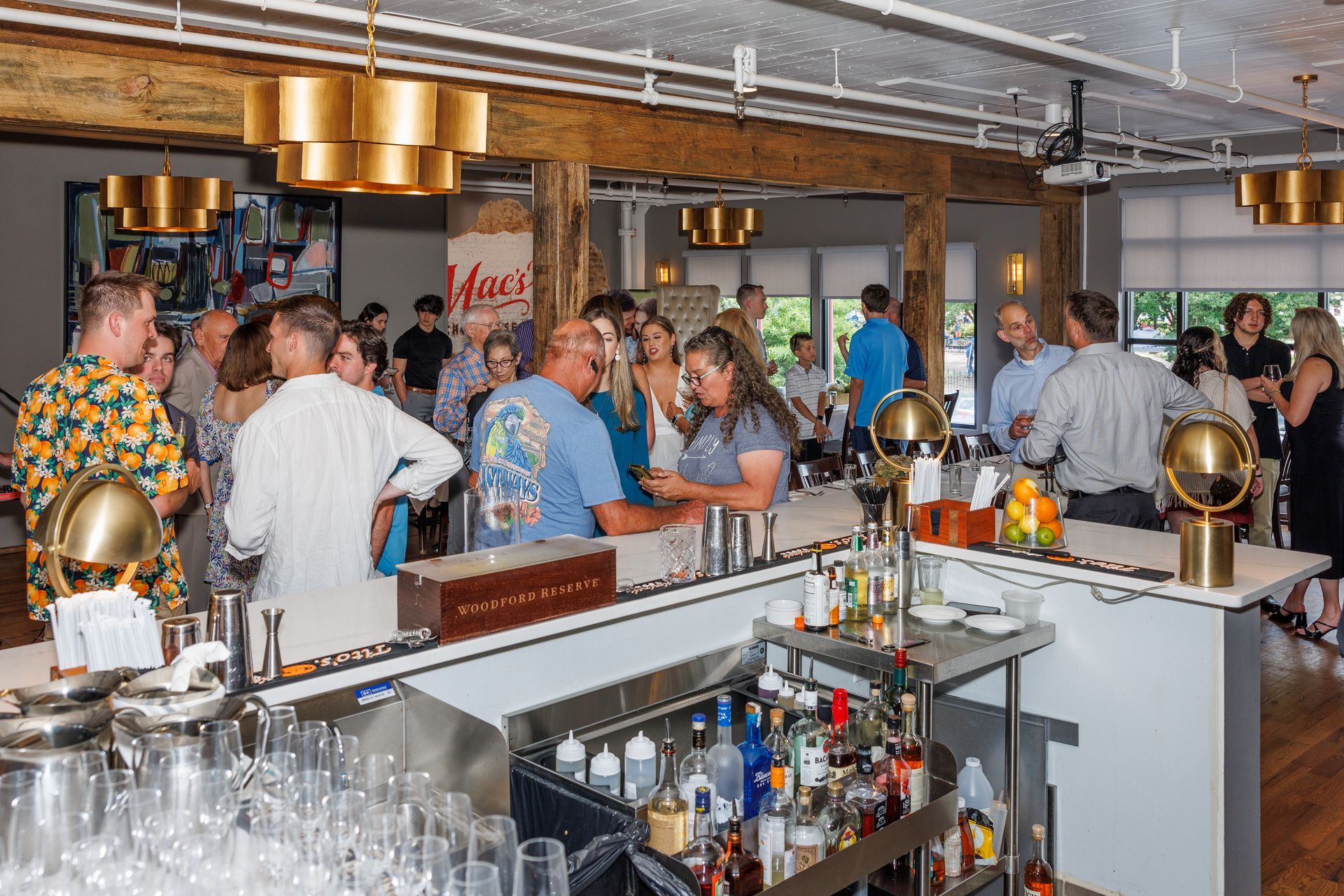 A group of people are standing around a bar in a restaurant.