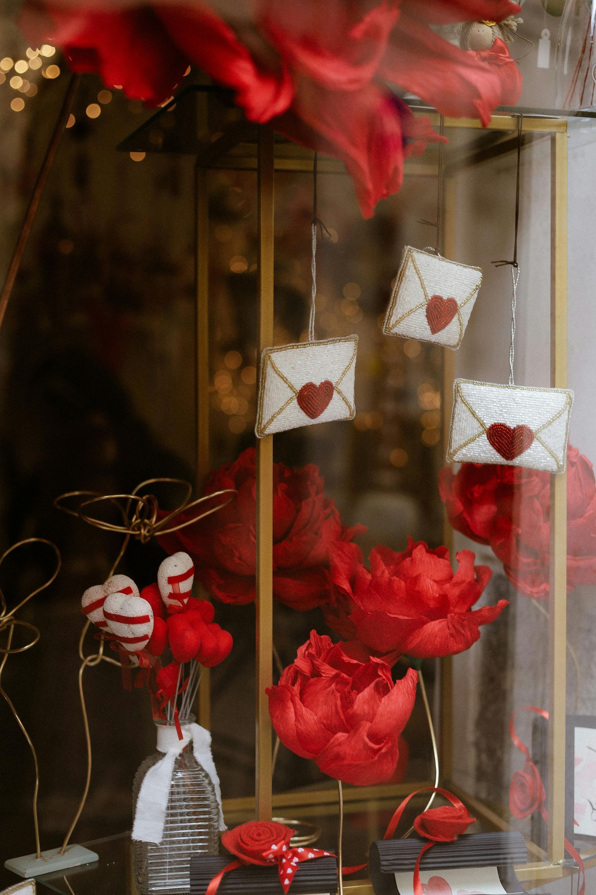 Decorazione natalizia rossa per San Valentino con cuori, fiori e piccole statuine di Babbo Natale in una teca di vetro.