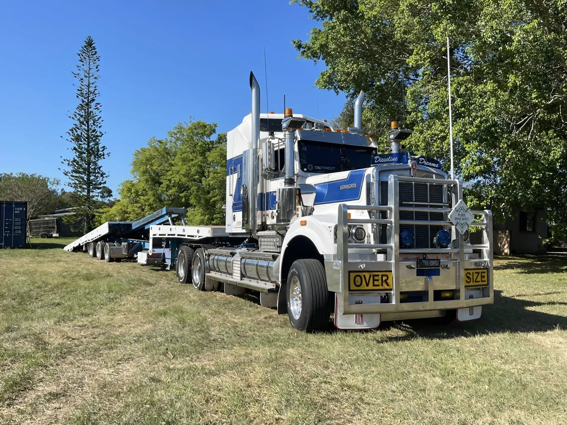 Semi-truck and trailer on grass, blue and white cab, sunny day — Supertilt Brisbane In Bracken Ridge, QLD