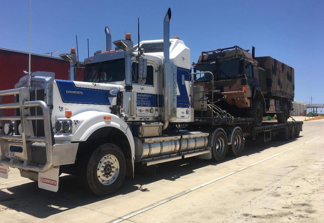 White and blue semi-truck hauling large industrial equipment on a flatbed trailer in a sunny setting — Supertilt Brisbane In Bracken Ridge, QLD