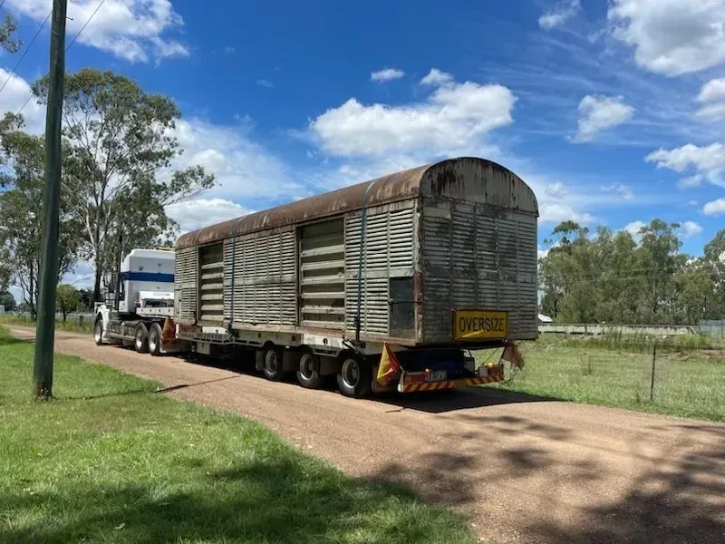 Semi-truck hauling a large, weathered, wooden stock trailer on a dirt road under a blue sky — Supertilt Brisbane In Bracken Ridge, QLD