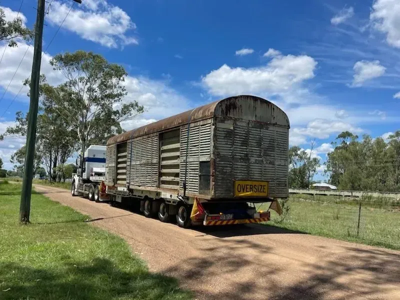 Truck hauling an oversized, weathered, wooden livestock trailer on a dirt road under a blue sky — Supertilt Brisbane In Bracken Ridge, QLD