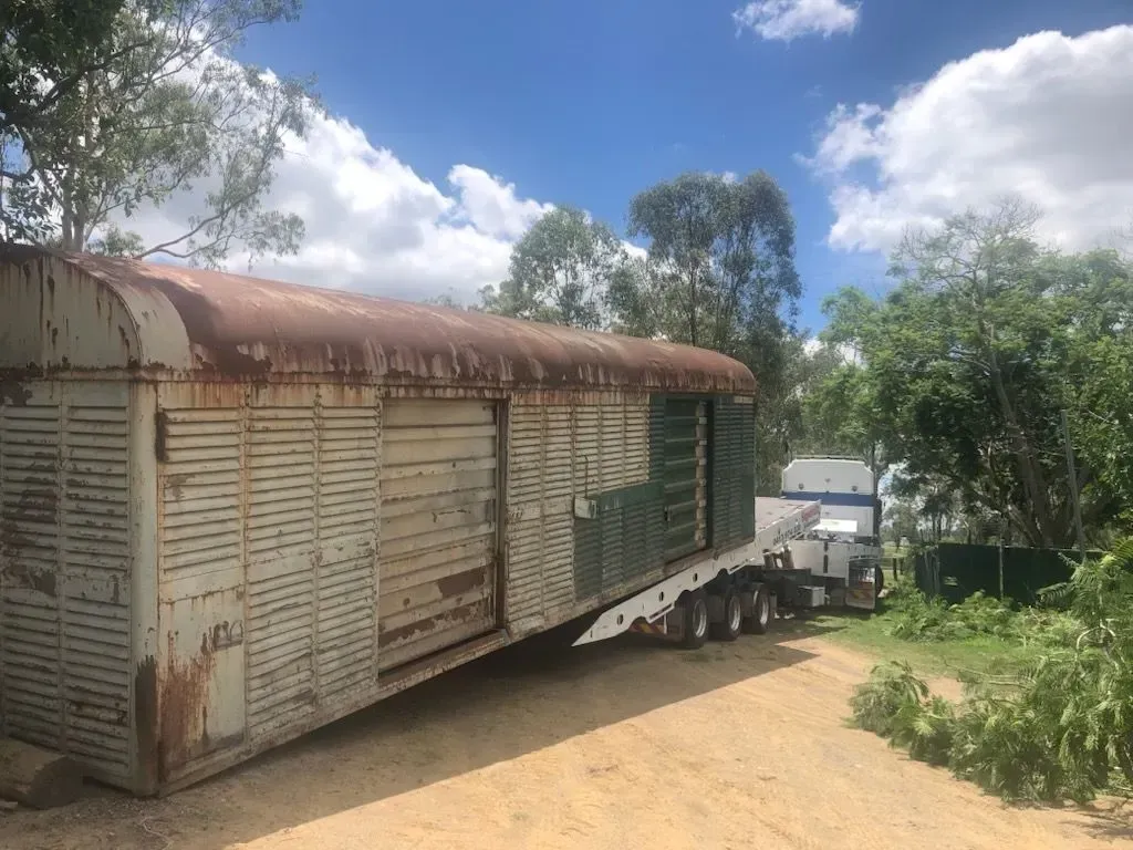 An old, rusty livestock trailer on a flatbed truck on a dirt road, trees in the background under a blue sky — Supertilt Brisbane In Bracken Ridge, QLD