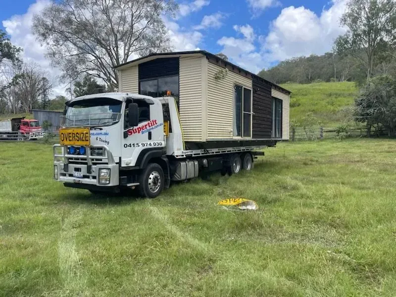 A Tiny Home on a flatbed truck in a grassy field. Truck has
