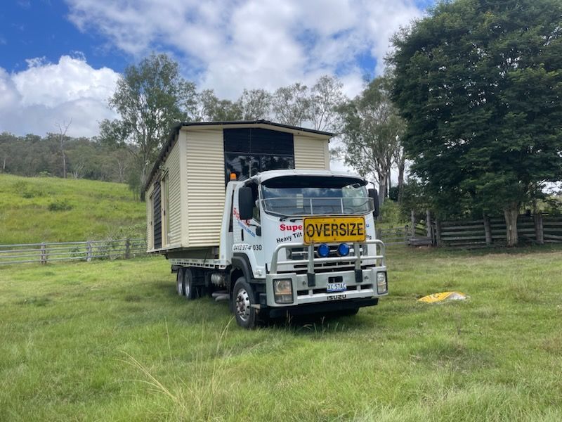 Truck Transporting a Tiny Home Across a Grassy Field — Supertilt Brisbane In Bracken Ridge, QLD