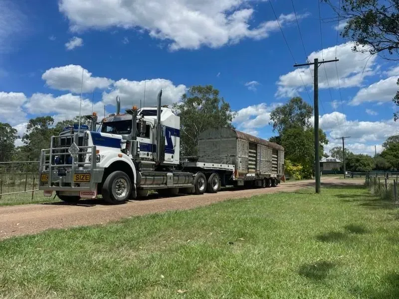 A semi-truck hauling a livestock trailer on a dirt road, under a blue sky with clouds — Supertilt Brisbane In Bracken Ridge, QLD