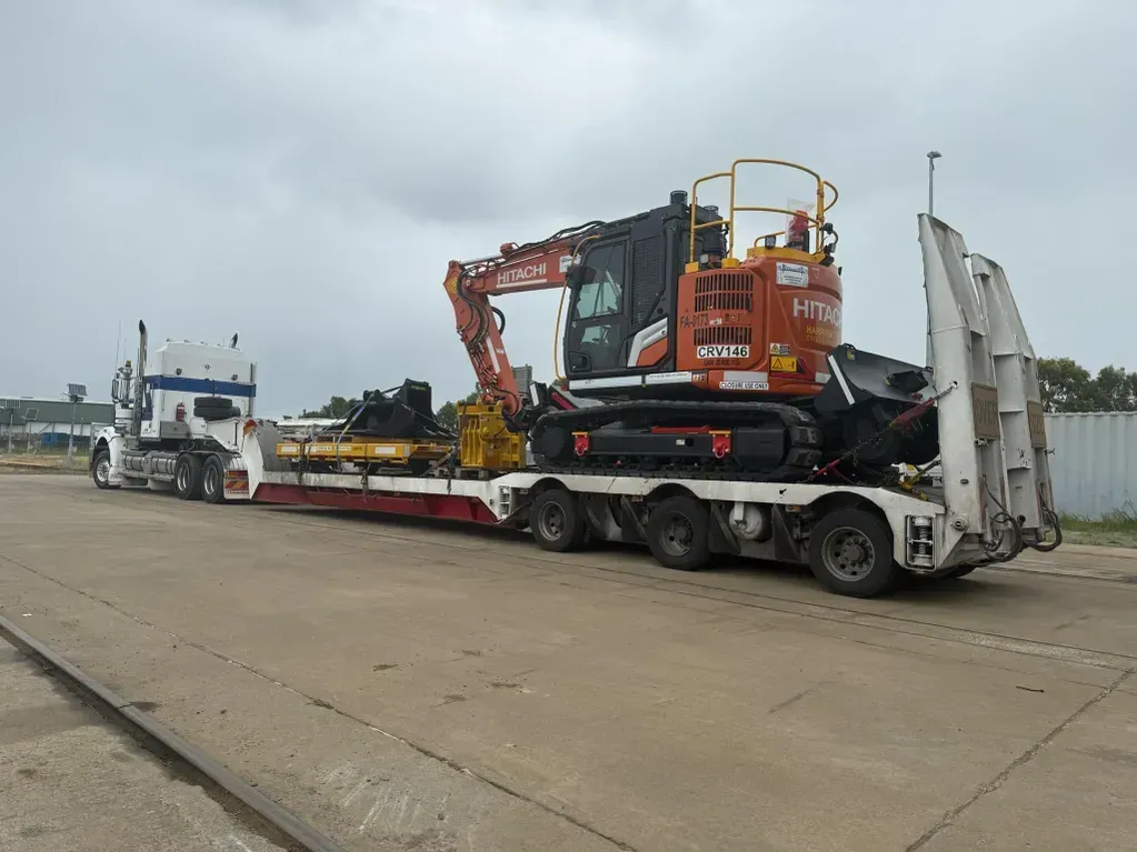 A Semi-truck Transporting an Orange Excavator on a Lowboy Trailer — Supertilt Brisbane In Pinkenba, QLD