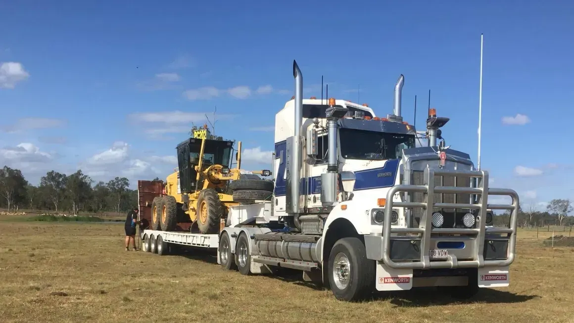 Semi-truck Transporting a Yellow Construction Grader on a Flatbed Trailer — Supertilt Brisbane In Port of Brisbane, QLD