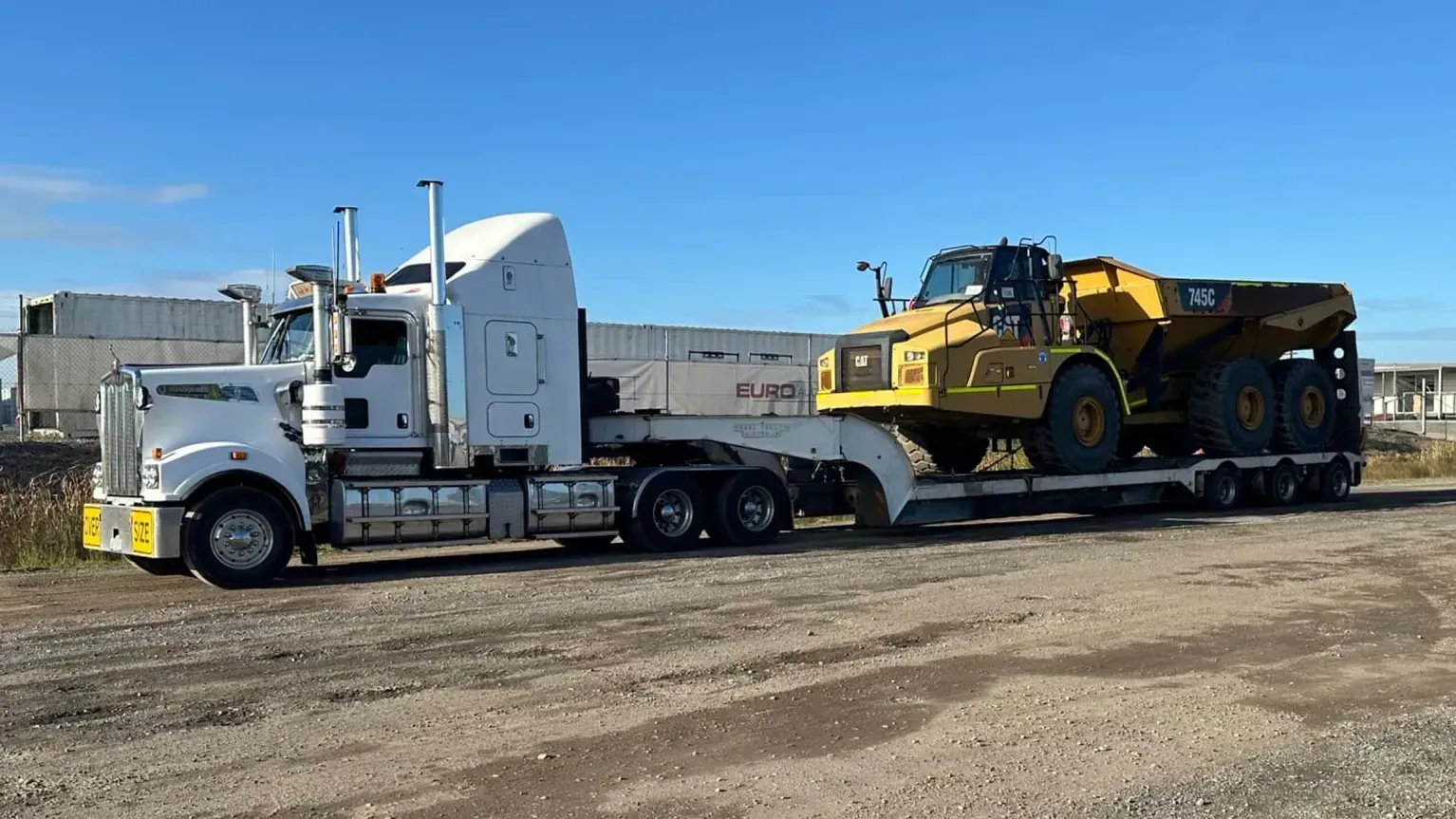 White Semi-truck Hauling a Large Yellow Dump Truck on a Flatbed Trailer — Supertilt Brisbane In Staplyton, QLD