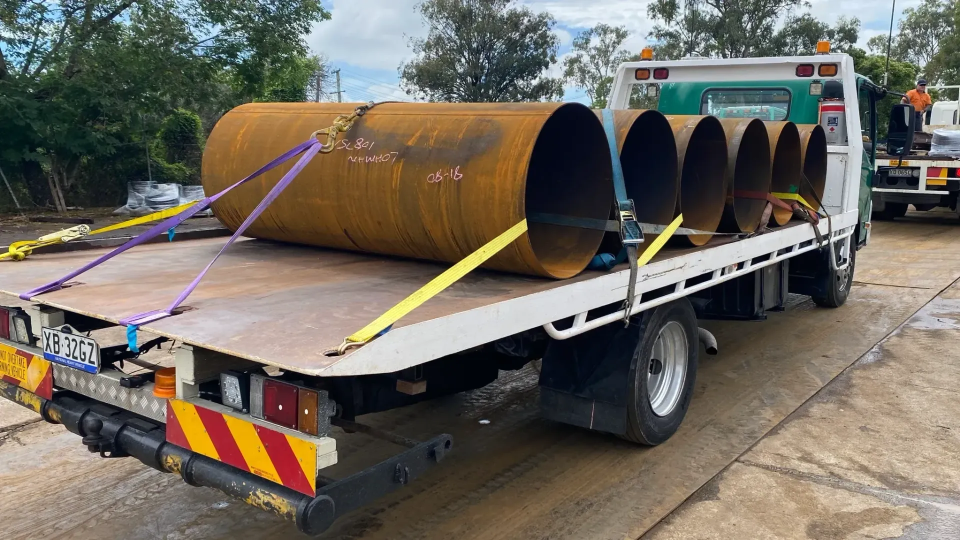 Flatbed Truck Transporting Several Large, Rusty Metal Pipes —— Supertilt Brisbane In Archerfield, QLD