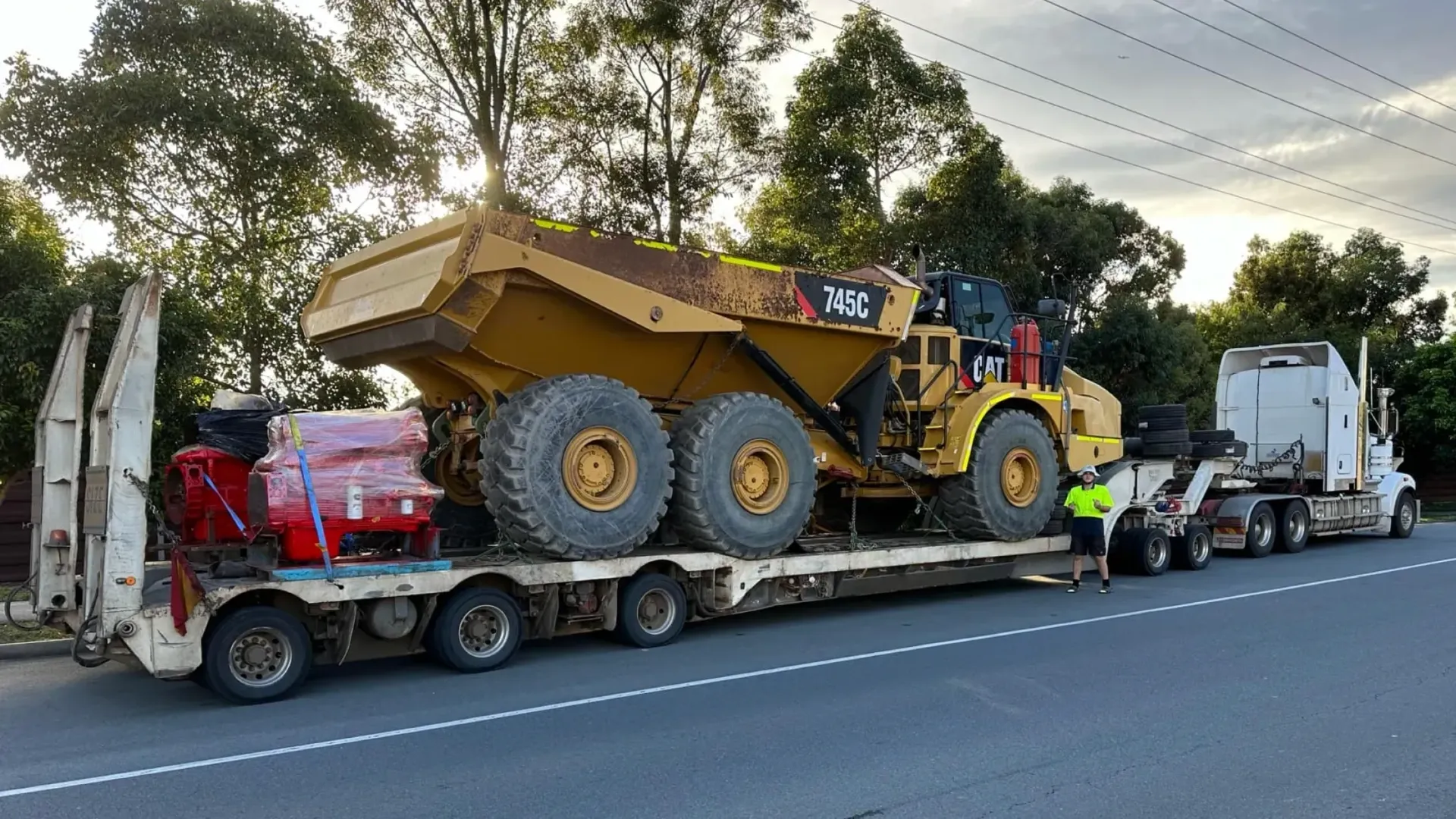 A Large Yellow Dump Truck is Being Transported on a Flatbed Trailer — Supertilt Brisbane In Rocklea, QLD