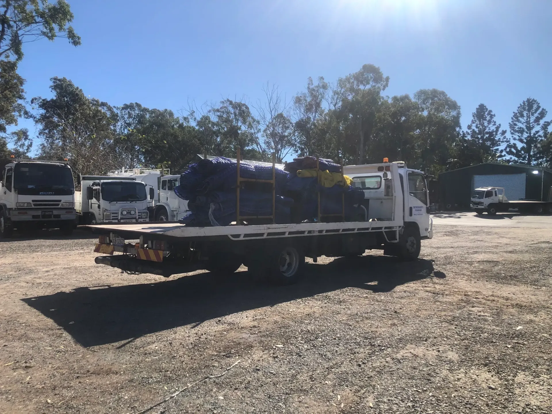 A White Flatbed Truck Loaded With Blue Tarps and Supplies — Supertilt Brisbane In Bracken Ridge, QLD