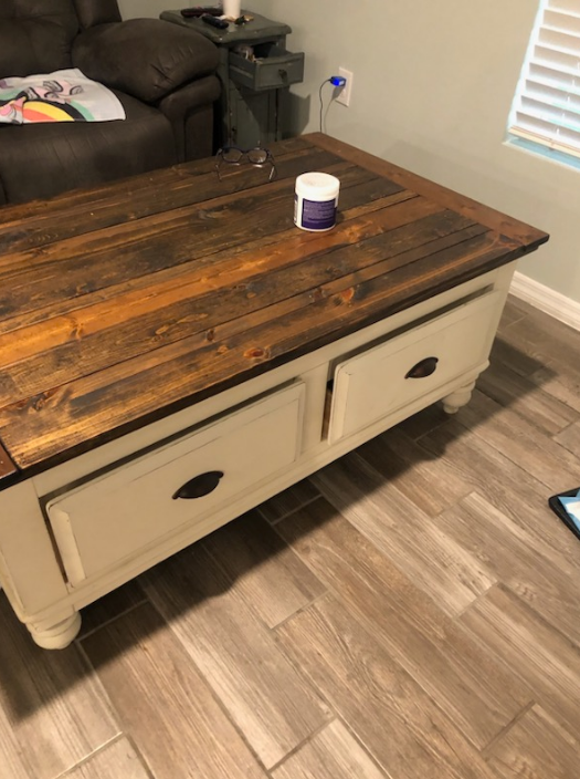 Wooden coffee table with two drawers, stained top, white base, and a paint can.