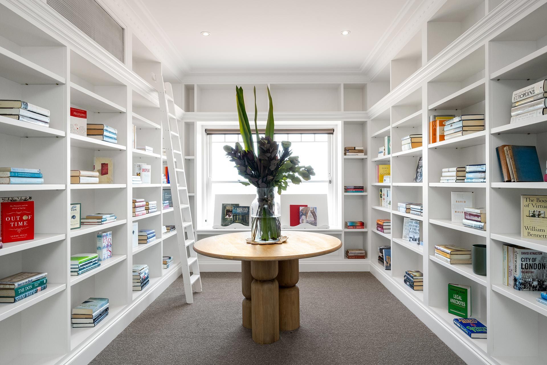 There is a table in the middle of a library filled with books. Beauty Point.