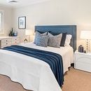 A bedroom with a bed , nightstand , lamps and a blue headboard. Palm Beach.