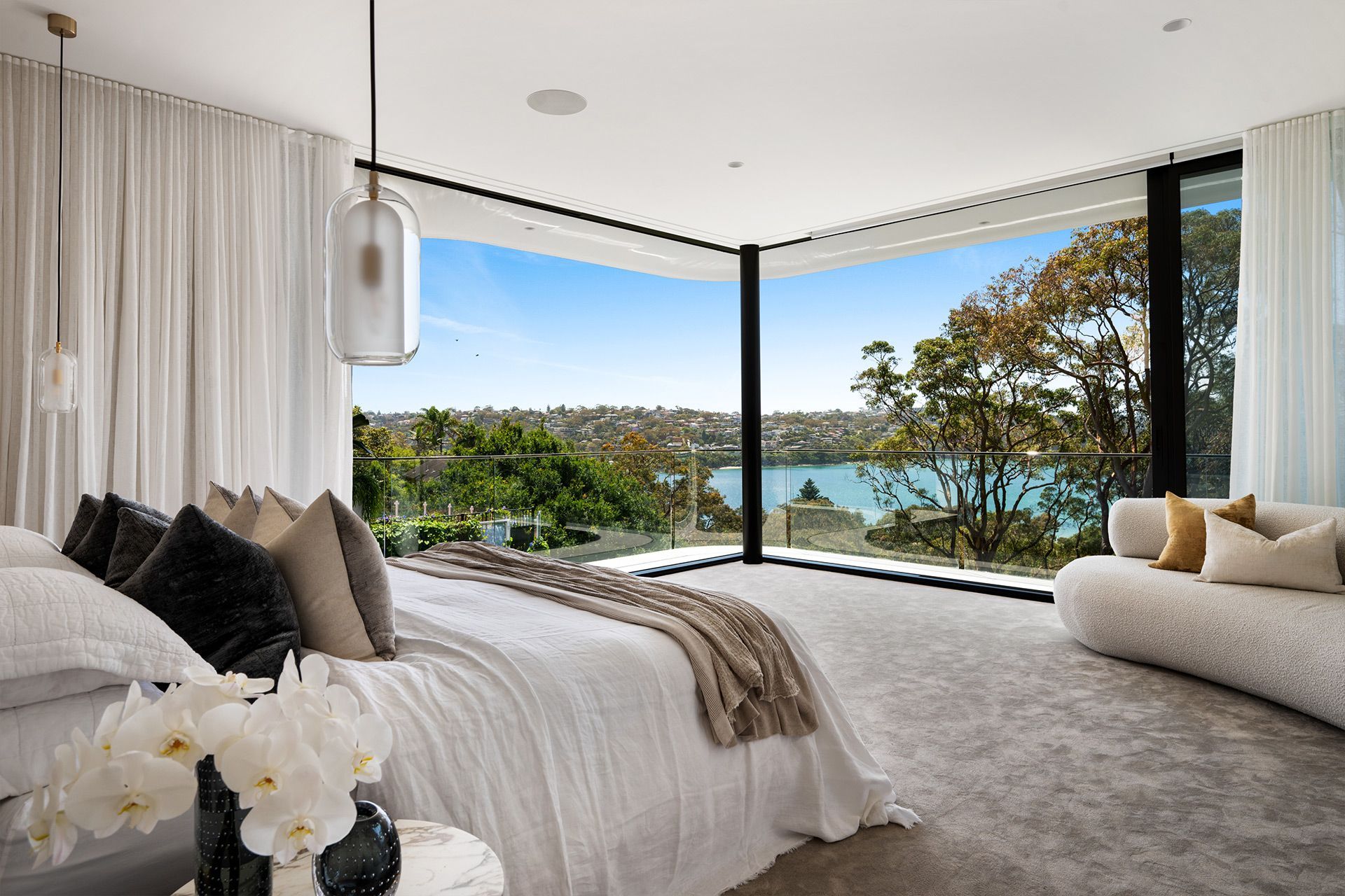 A bedroom with a large bed and a large window overlooking a lake.