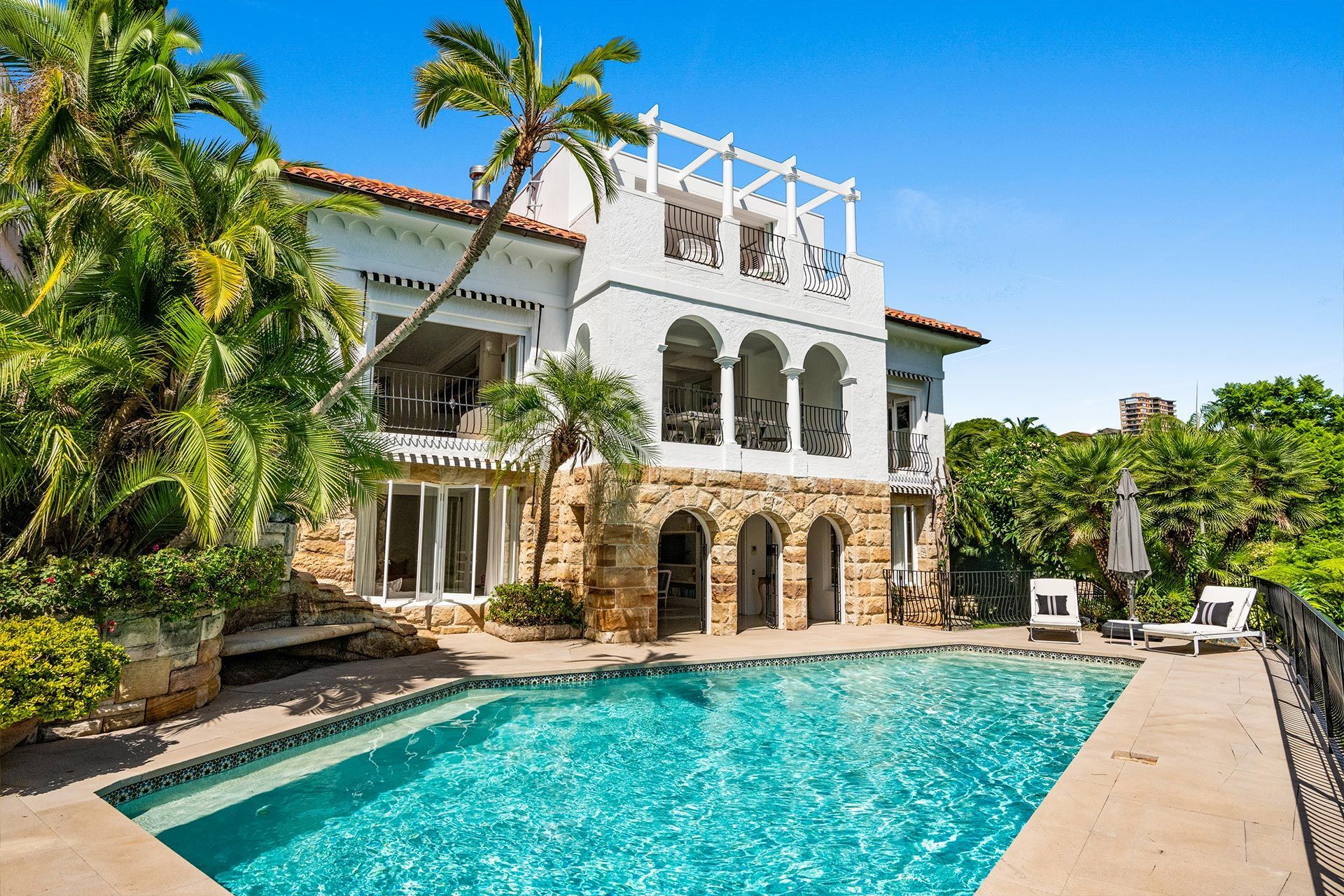 A large white house with a large swimming pool in front of it.