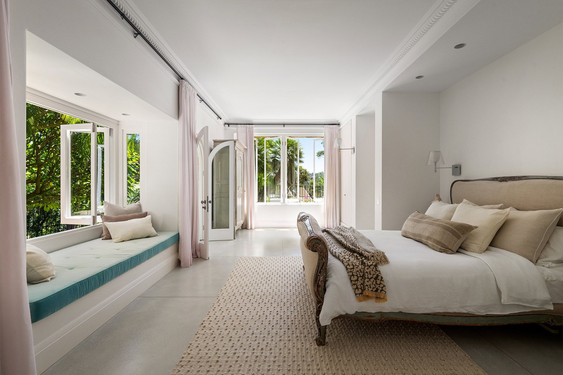 A bedroom with a large bed and a window seat.