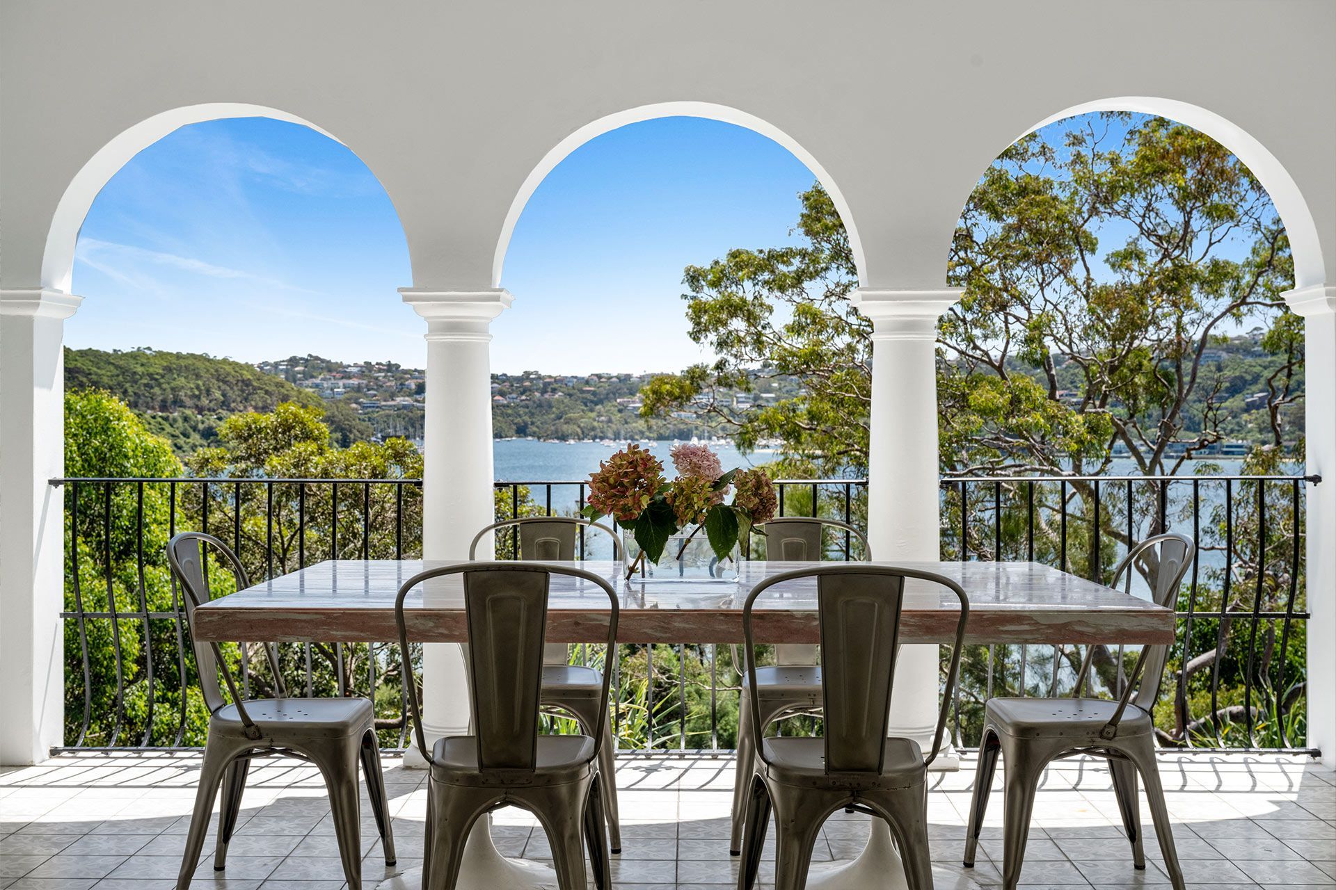 A dining table and chairs on a balcony overlooking a lake.