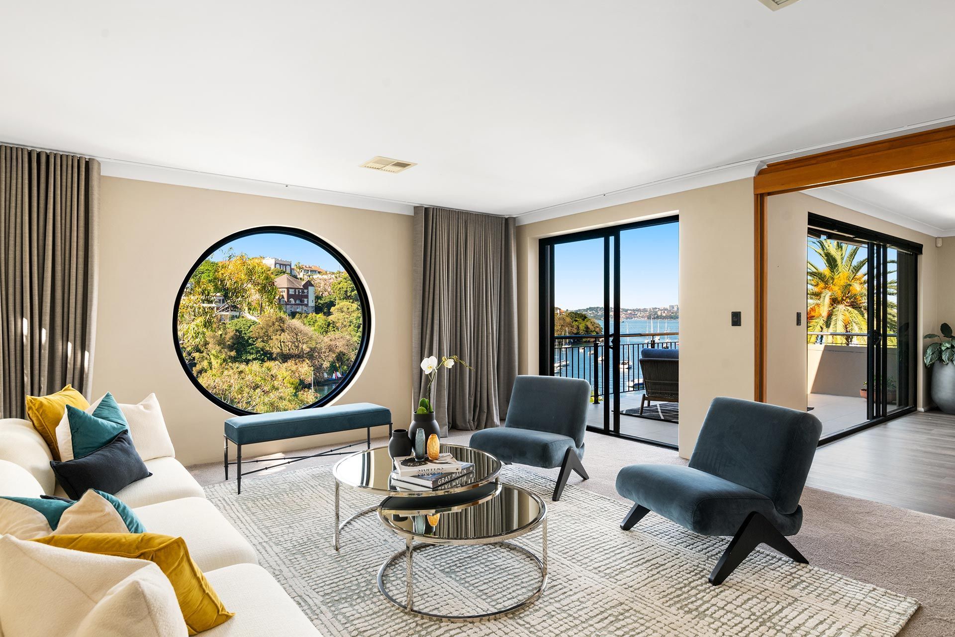 A living room with a couch , chairs , and a round window.