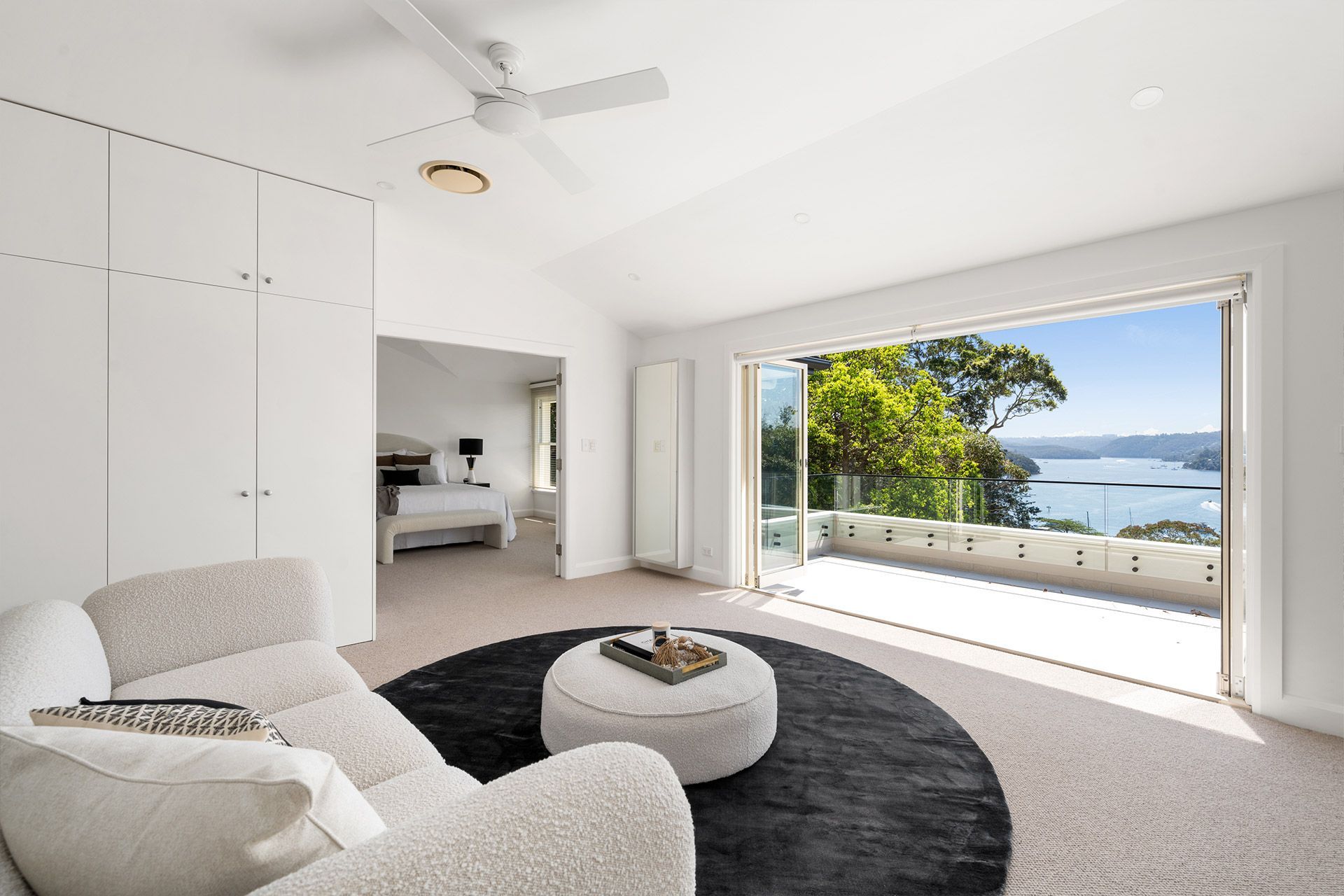 A living room with a couch , chair and ottoman with a view of the ocean.
