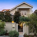 A large house with a fence and trees in front of it. Manly.