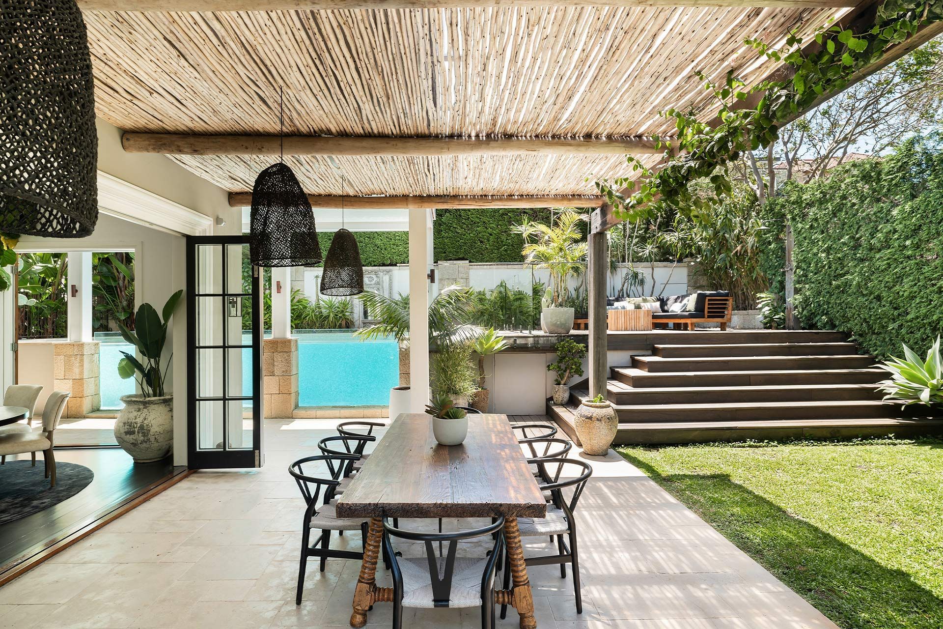 There is a table and chairs under a pergola in the backyard.