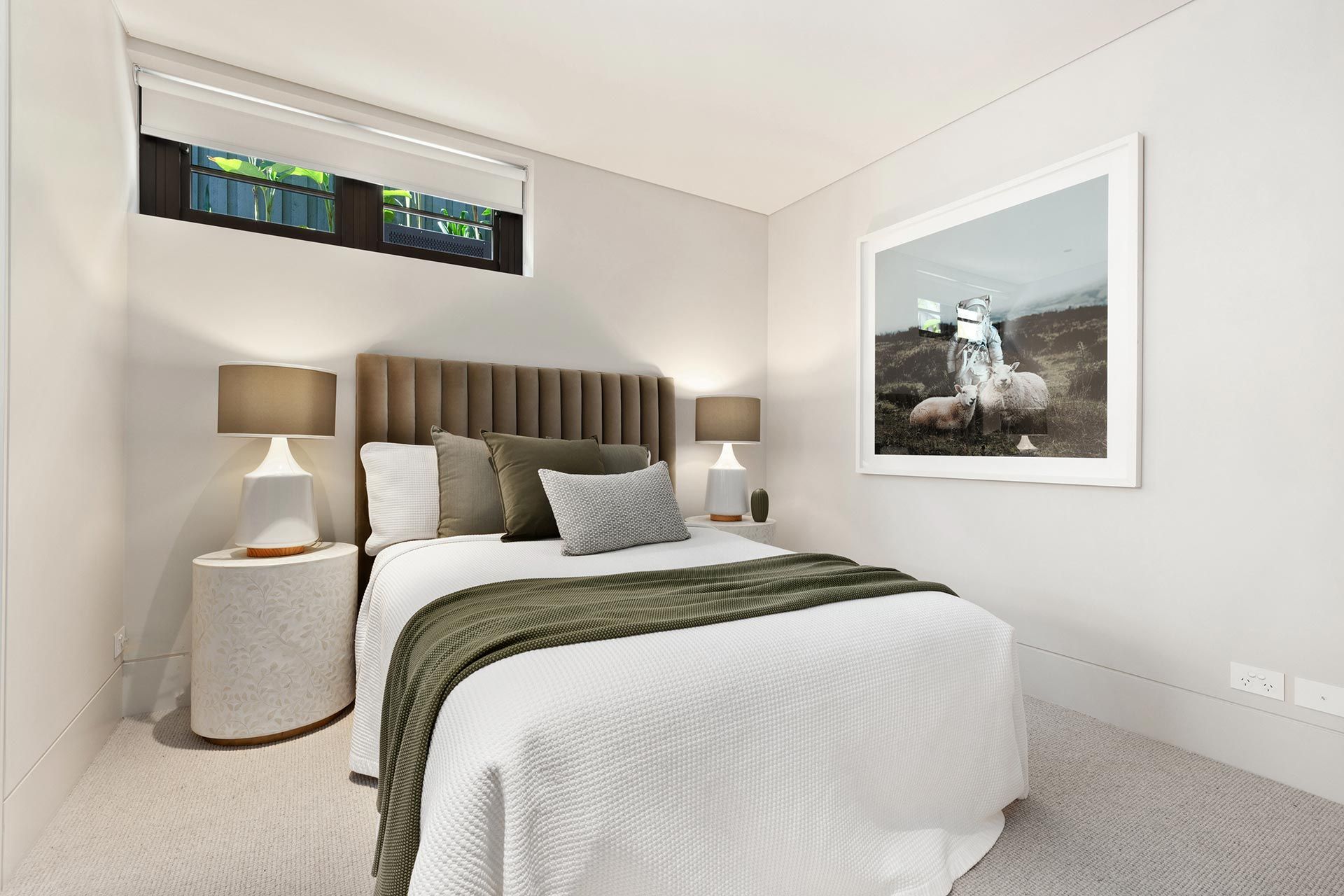 A bedroom with a bed , nightstand , lamps and a picture on the wall.