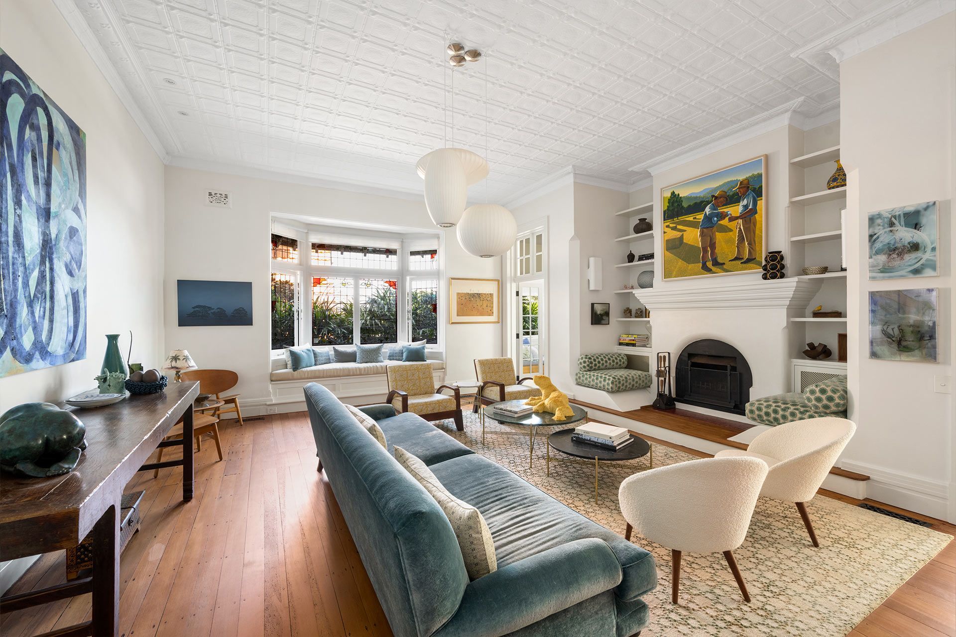 A living room with a blue couch , white chairs , and a fireplace.