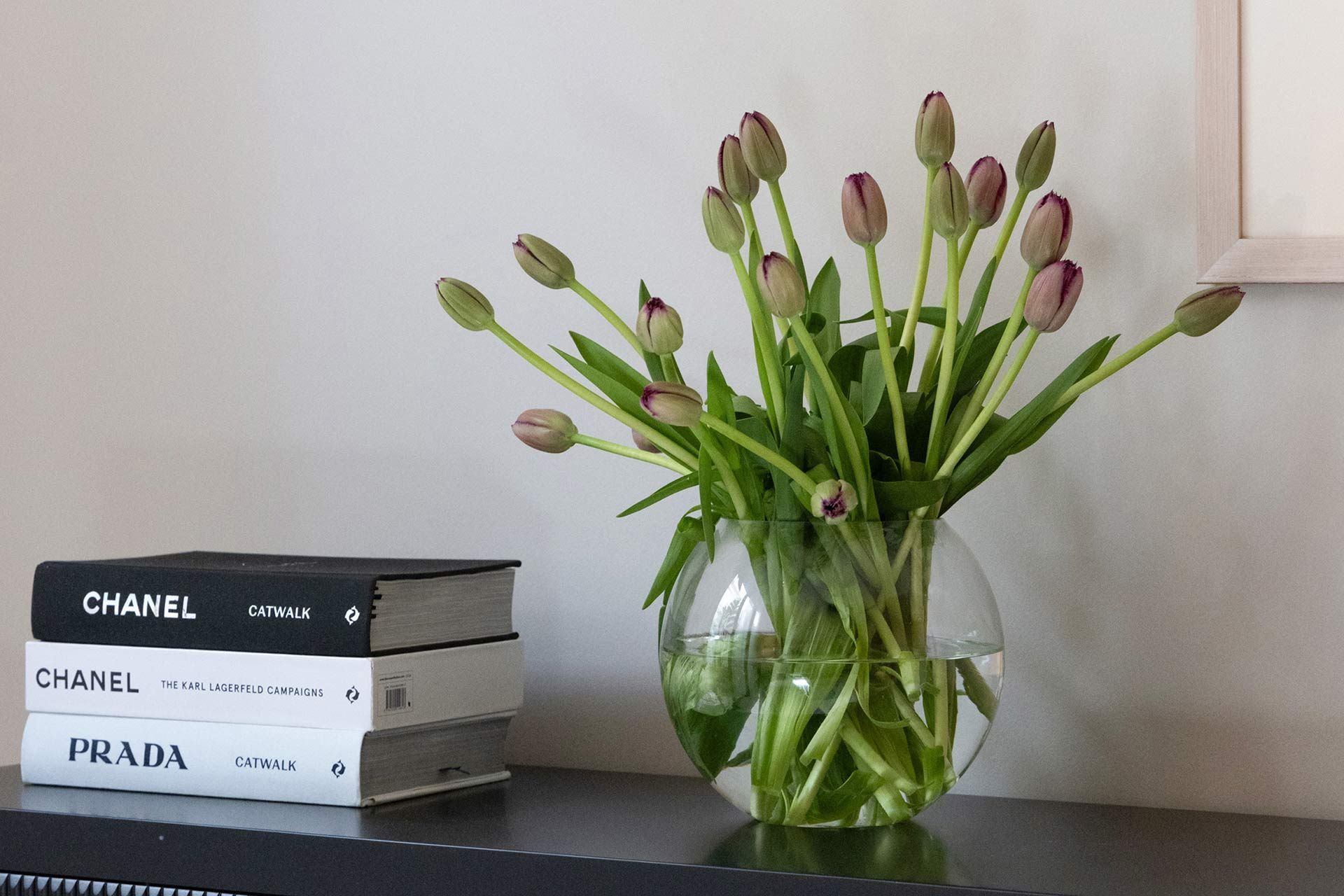 A vase of flowers sits on a table next to a stack of chanel books. Cremorne