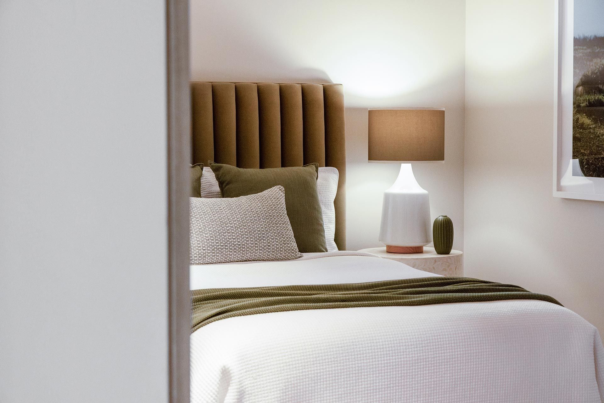 A bedroom with a bed , lamp and picture on the wall.