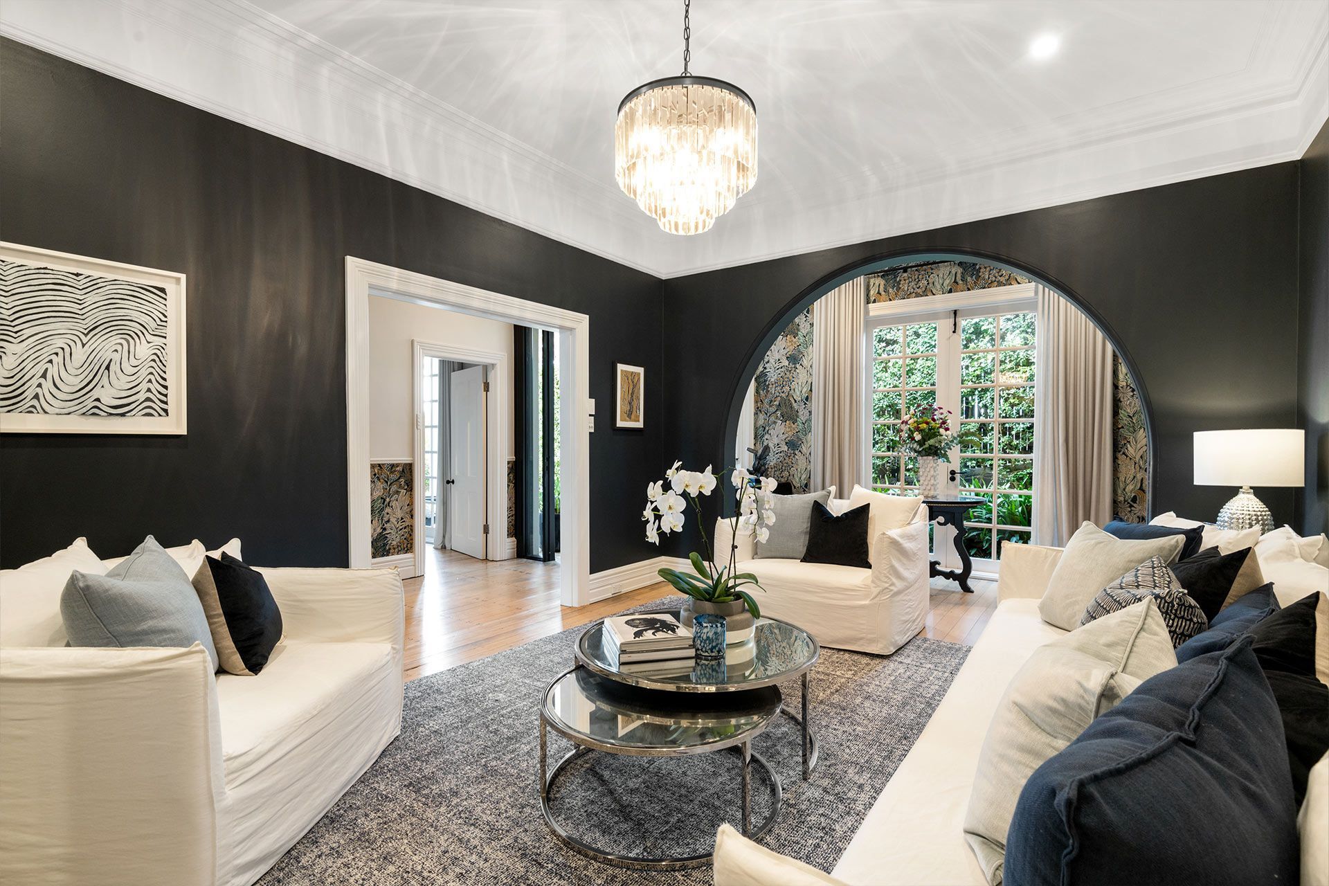 A living room with black walls and white furniture and a chandelier.