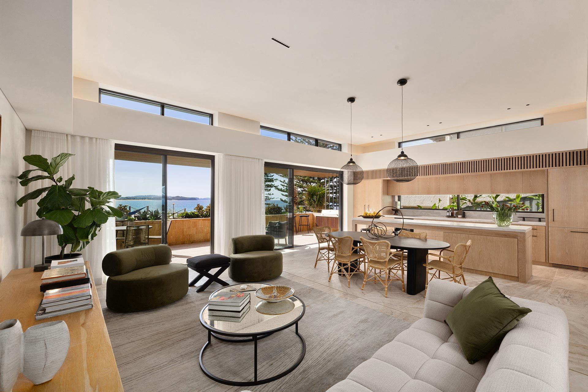 A living room with a couch , chairs , a table and a view of the ocean.