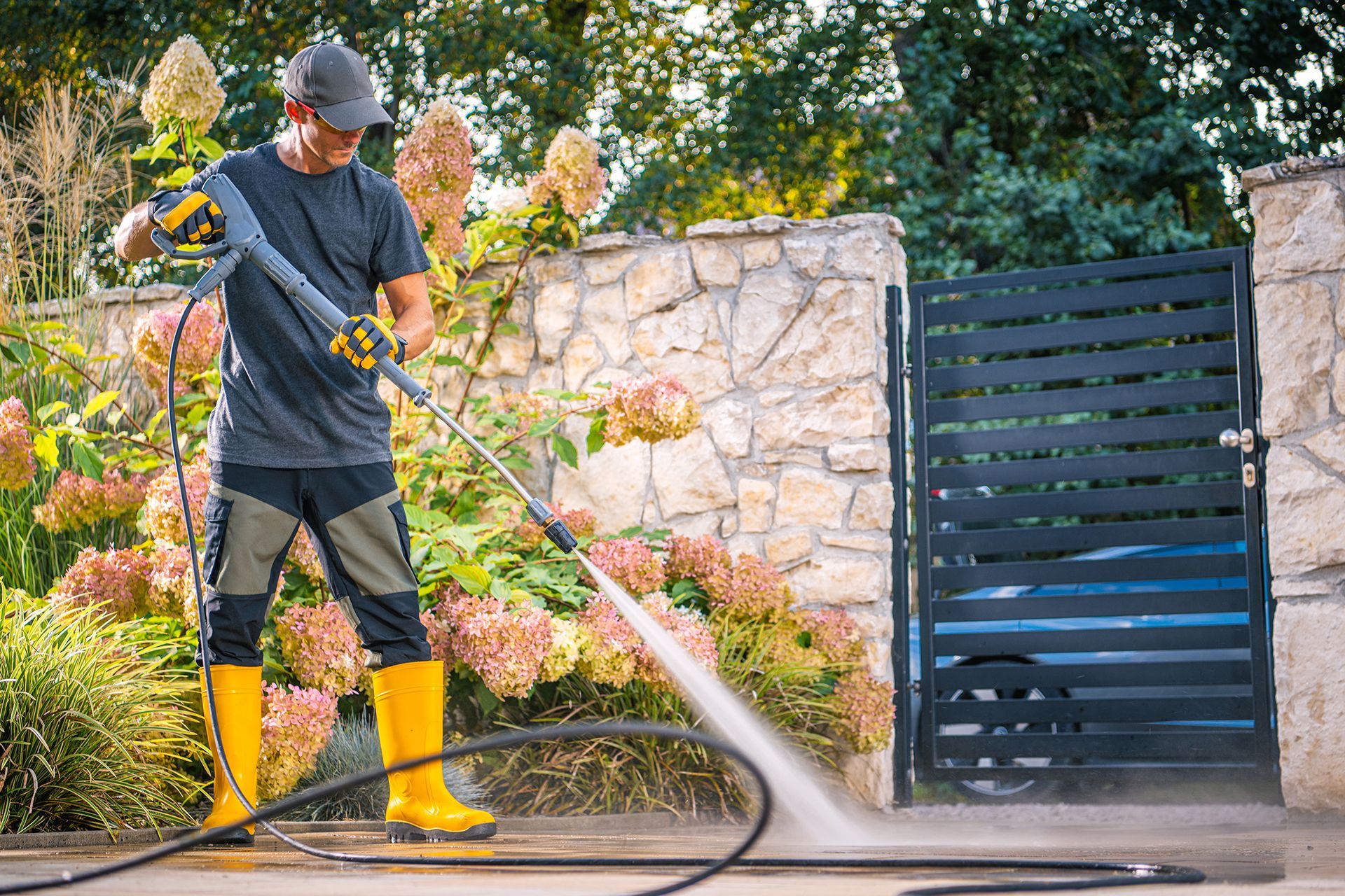 A man is using a high pressure washer to clean a driveway.