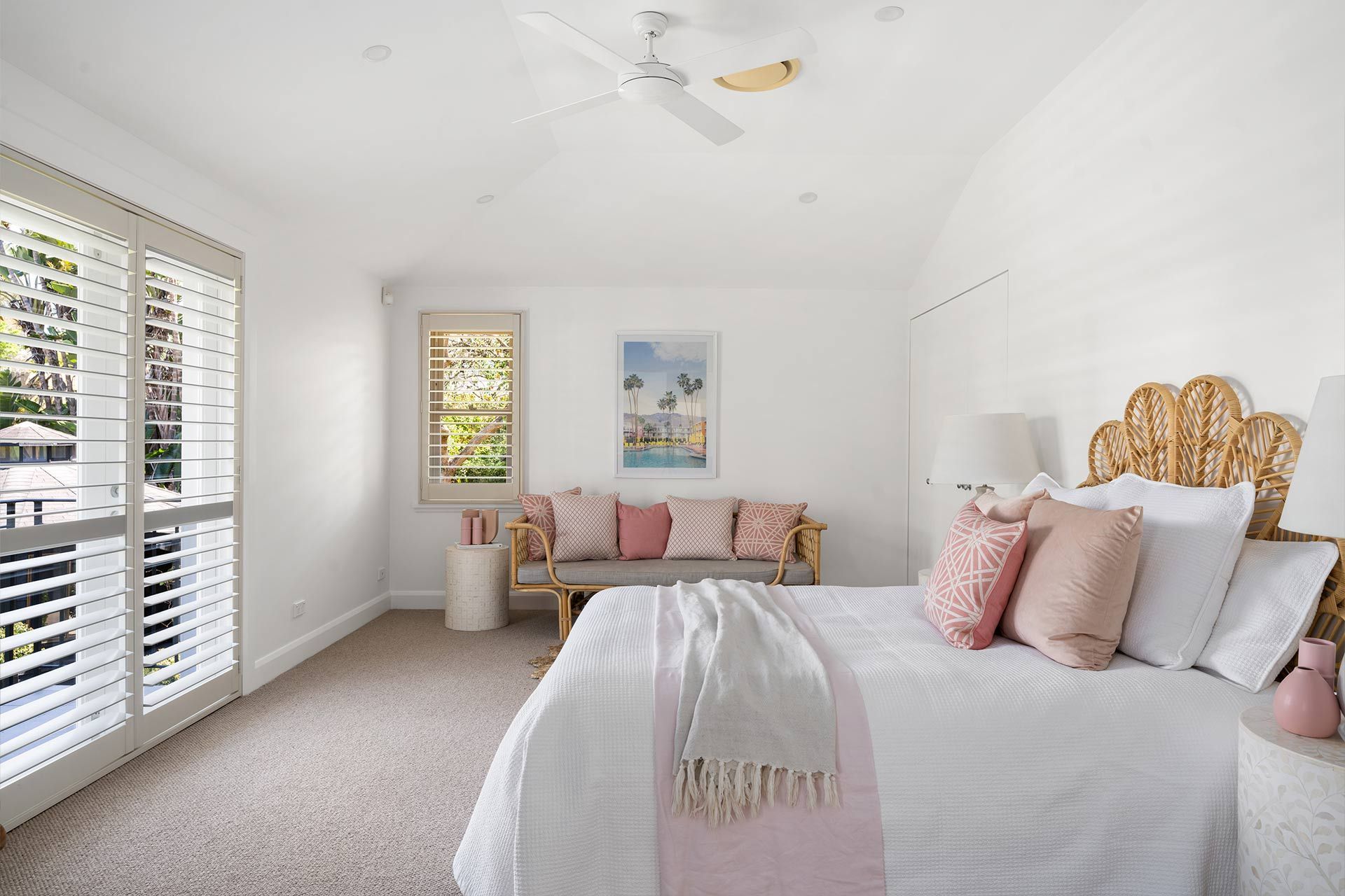 A bedroom with a bed , couch , and a ceiling fan.