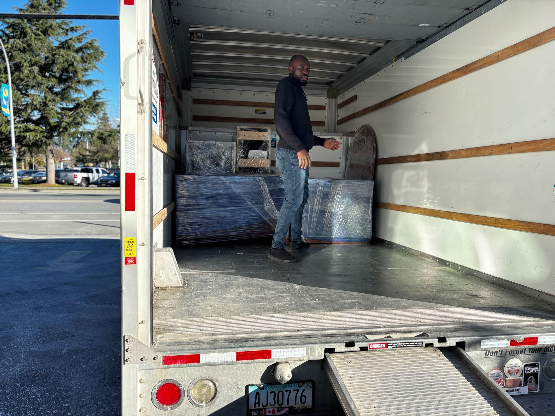 A man is standing in the back of a moving truck.