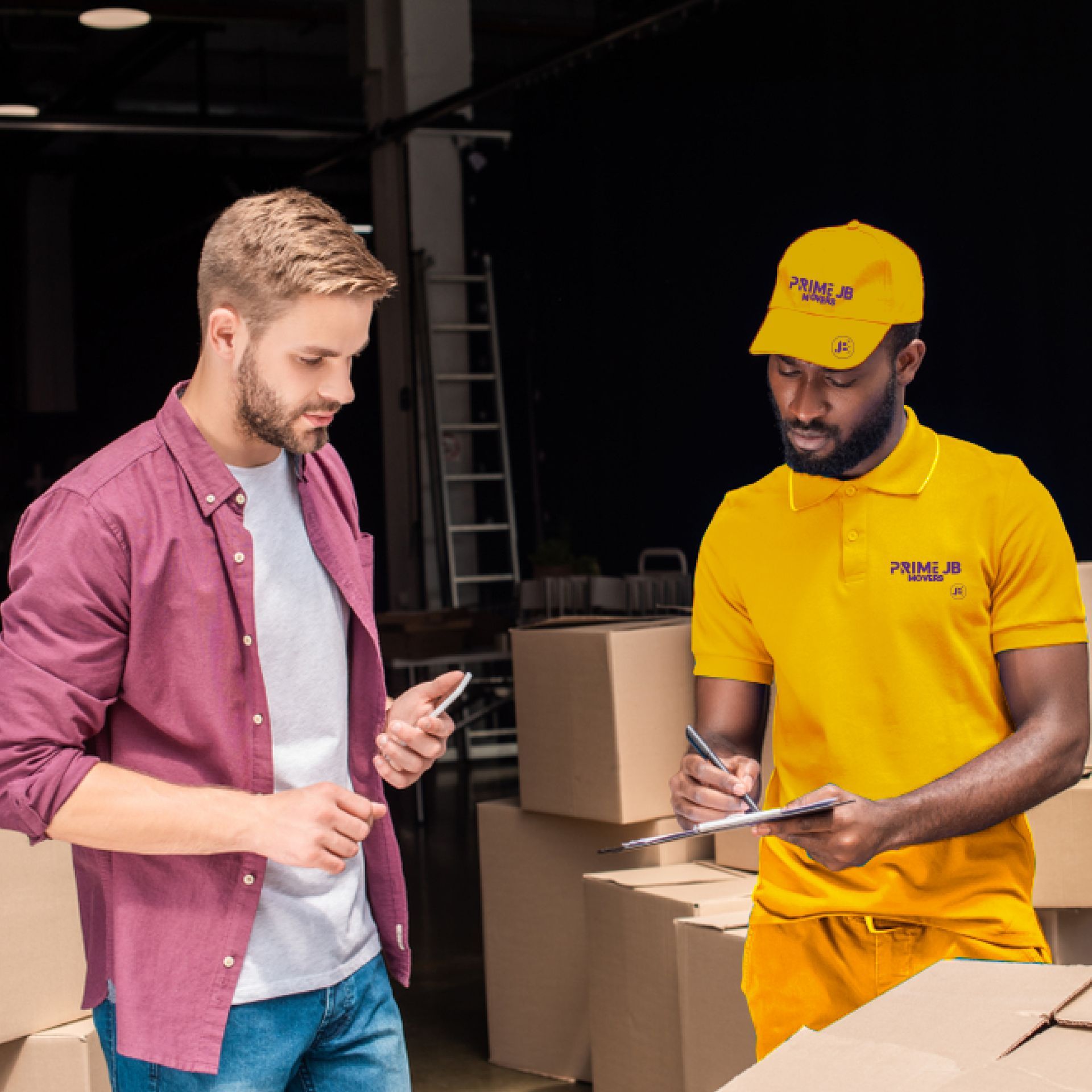 Two men are standing next to each other in a warehouse looking at a clipboard.