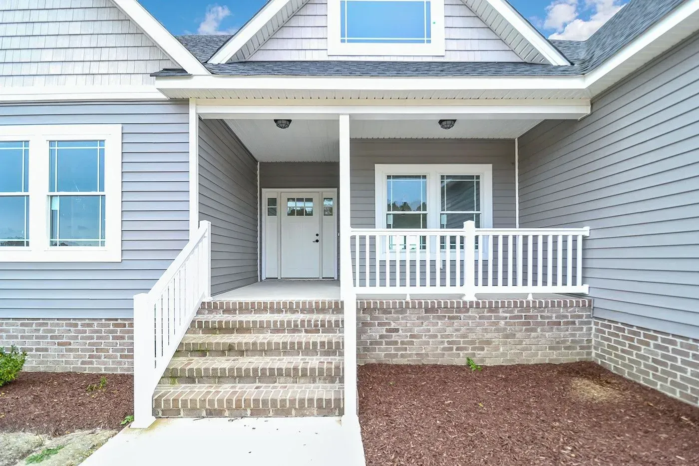 Gray house exterior with porch, steps, and white railing.