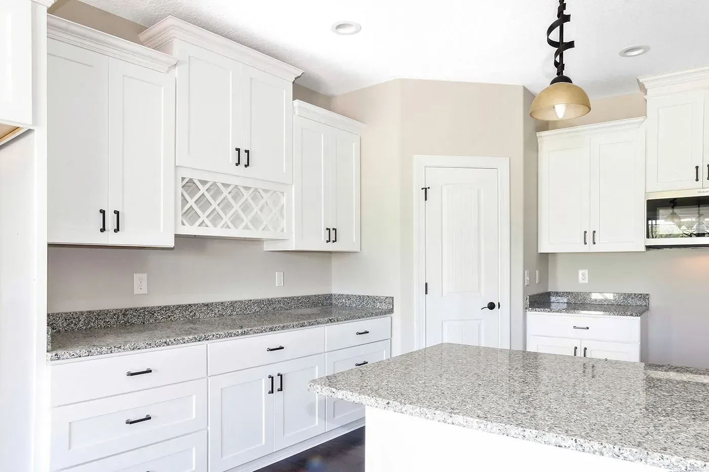 White kitchen cabinets with granite countertops and island.